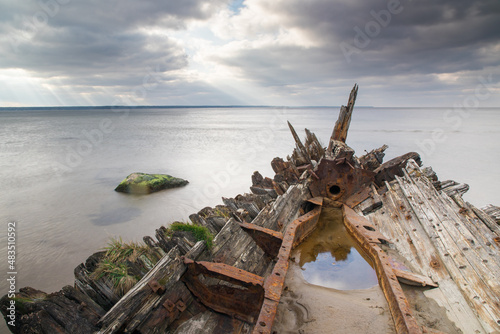 Fototapeta Naklejka Na Ścianę i Meble -  A view of an old wrecked wooden boat on the beach of the Baltic Sea, Lahemaa, Estonia