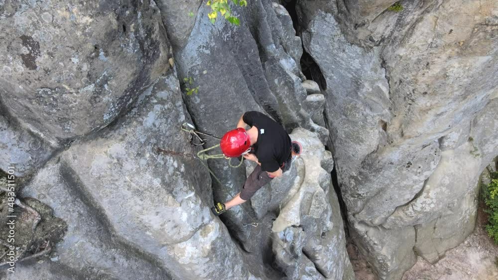 Strong male climber climbing steep wall of rocky mountain. Sportsman overcoming difficult route. Engaging in extreme sports hobby concept Strong male climber climbing steep wall of rocky mountain. Sportsman overcoming difficult route. Engaging in extreme sports hobby concept