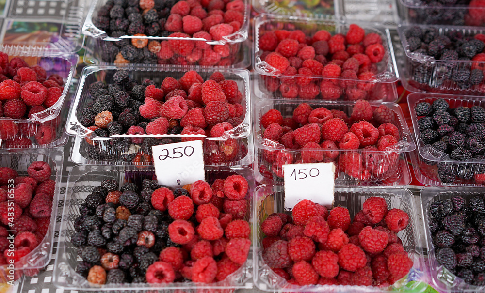 Red and black raspberries in plastic containers Red and black raspberries in plastic containers