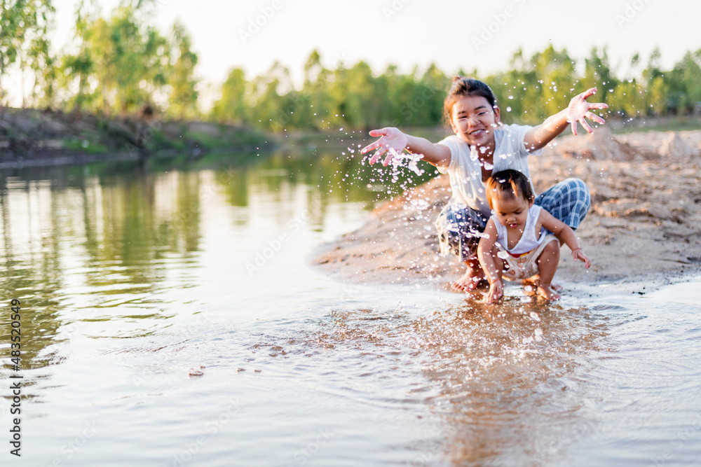 Fototapeta premium happy family Mother and little daughter playing in the water on the beach on a sunny day.