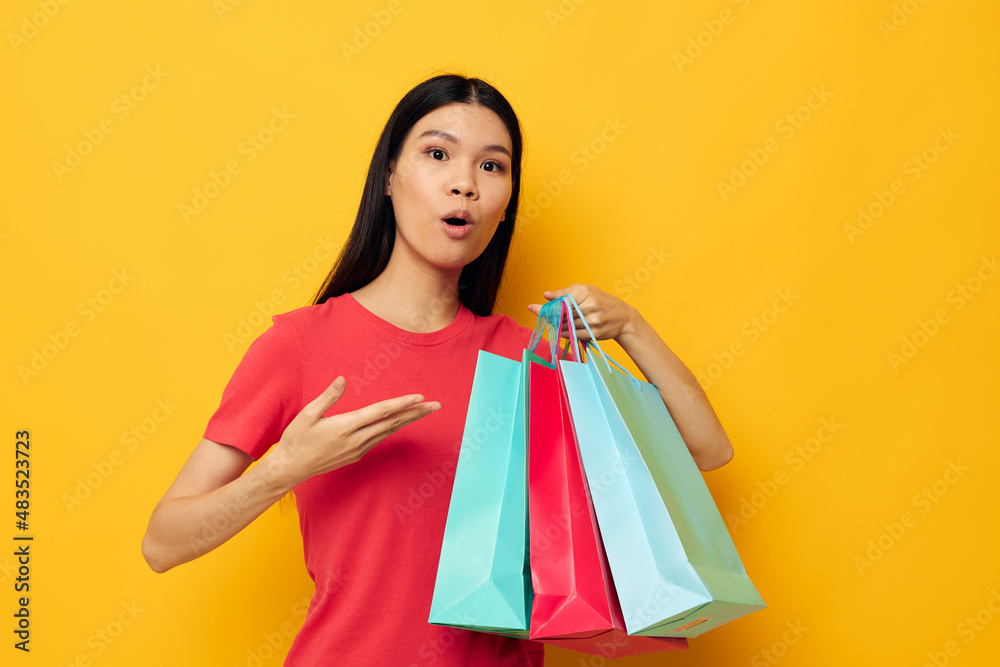 woman with Asian appearance shopping bags in red t-shirt isolated background unaltered woman with Asian appearance shopping bags in red t-shirt isolated background unaltered