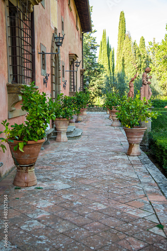 Fountains, terracotta walls and tall trees of a Tuscan villa, Italy