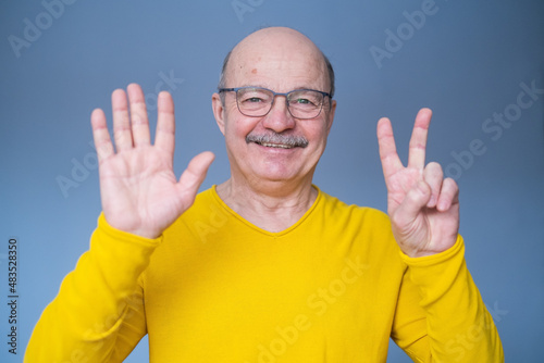 Senior man raising hand, showing number seven with fingers, counting something © Viktor Koldunov