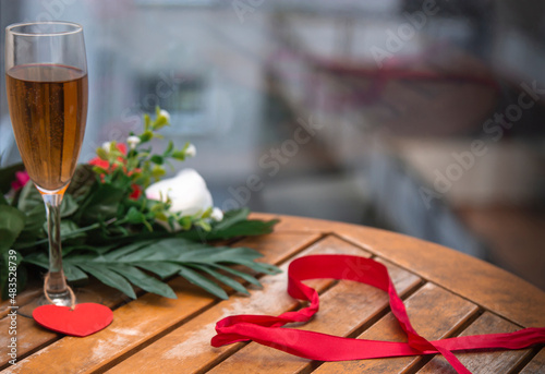 Heart shaped ribbon with champagne glass and rose flowers on background. Happy Valentine's day, mother's day, birthday concept. Flat lay romantic composition.