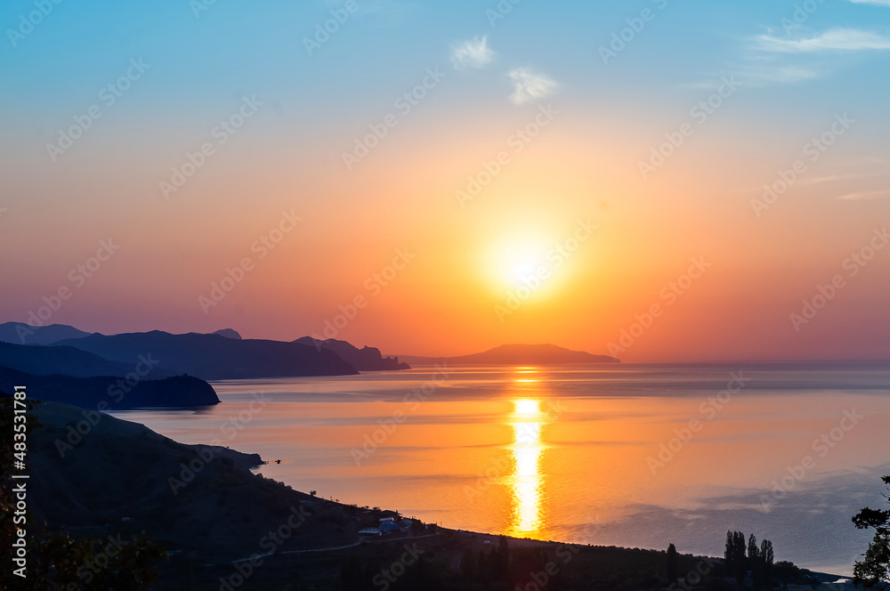 Amazing colorful, beautiful sunrise over mountains and deep blue sea. Scenic view of the sea and mountains in the distance at sunset.