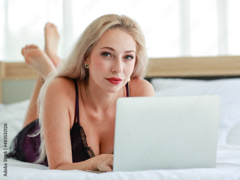 Closeup studio shot of Caucasian woman blonde hair hot female fashion model in black sexy lingerie underwear lay down smiling browsing surfing internet online via laptop on bed in bedroom Closeup studio shot of Caucasian woman blonde hair hot female fashion model in black sexy lingerie underwear lay down smiling browsing surfing internet online via laptop on bed in bedroom