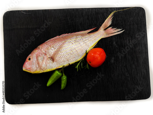 Fresh Pink Perch (thread finned Bream) Decorated with vegetables on a wooden pad,Black Background,Selective focus photo