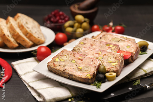 Sliced Traditional French terrine covered with bacon on dark wooden background