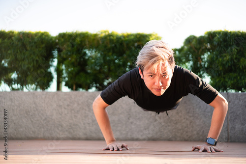 Active Asian young man making an outdoor body weight exercise. © DG PhotoStock