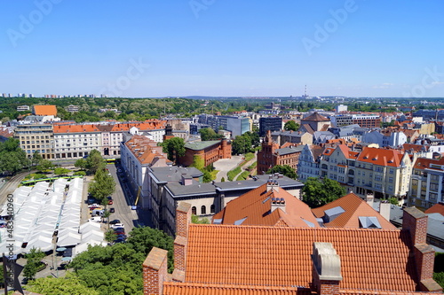 Roofs, buildings, umbrellas of the city market, trams and tram rails - a view of the historical part of the city of Poznań from above