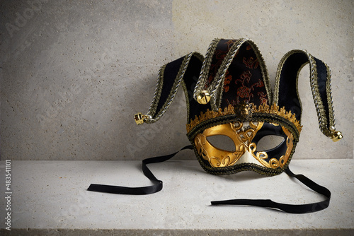 Venice carnival mask on travertine stone wall.