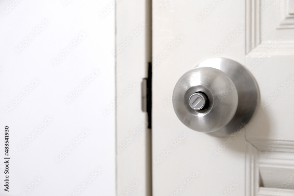 Stainless steel door knob or the handle on the wooden door In a brightly lit room. concept of cleanliness and hygiene. Stainless steel door knob or the handle on the wooden door In a brightly lit room. concept of cleanliness and hygiene.