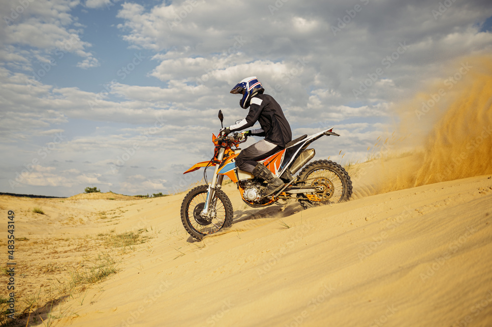 Professional motocross rider sliding down sand hill Professional motocross rider sliding down sand hill
