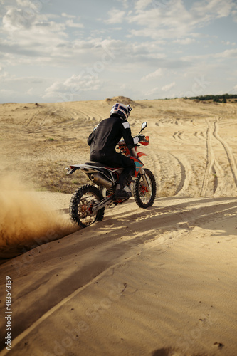 Professional motocross rider driving on sand dune