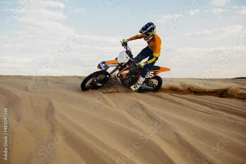 Rider making stunt on motorbike sliding sand