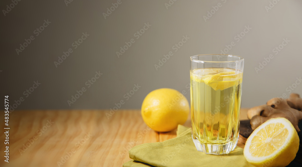 Fototapeta premium Glass of Infusion Ginger lemon drink. Organic and Healthy Lifestyle. Fresh Water with lemon Sliced. present on Table with Natural light. Seasonal Beverage