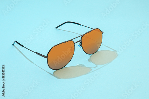 Aviator Sunglasses on blue background. Fashion sunglasses with sunlight for summer concept. Gold gradient on mirror lens aviator.