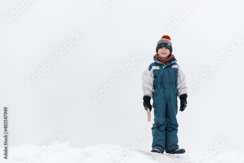 Boy plays outside during snowfall. Winter holidays. Child walks outdoors in winter.