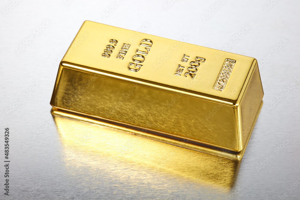 Ein Goldbarren liegt auf einem spiegelnden Untergrund.