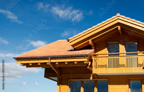 Neubau Holzhaus aus Massivholz im alpinen Stil nach traditioneller Art mit Dachgaube und Balkon photo