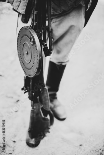 Man Re-enactor Dressed As World War II Soviet Russian Red Army Soldier Holding World War II Weapon Degtyaryov DP Machine Gun. WWII WW2 Russian Ammunition. Photo In Black And White Colors. photo