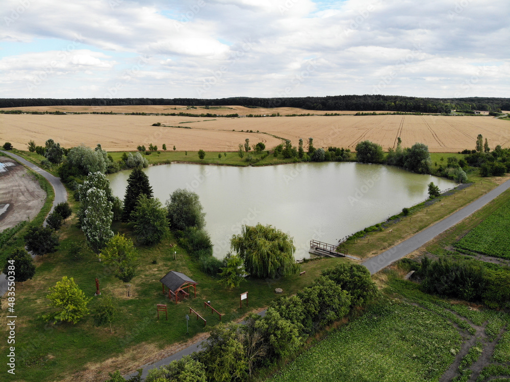 Obraz premium Photos of nature from a height. We see a field, a bike path and a heart-shaped pond.