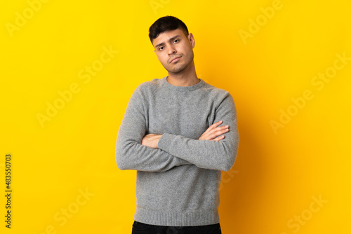Young Colombian man isolated on yellow background feeling upset
