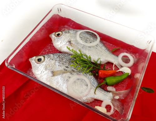 Gerres Fish (Gerres Filamentosus) Whipfin silver biddy Fish, Decorated with vegetables on a glass bowl, White Background.Selective Focus photo