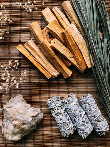 incense on a bamboo brown stand close-up, palo santo from Peru and California white sage, dried flowers around. Art background for text with natural incense and light background blur