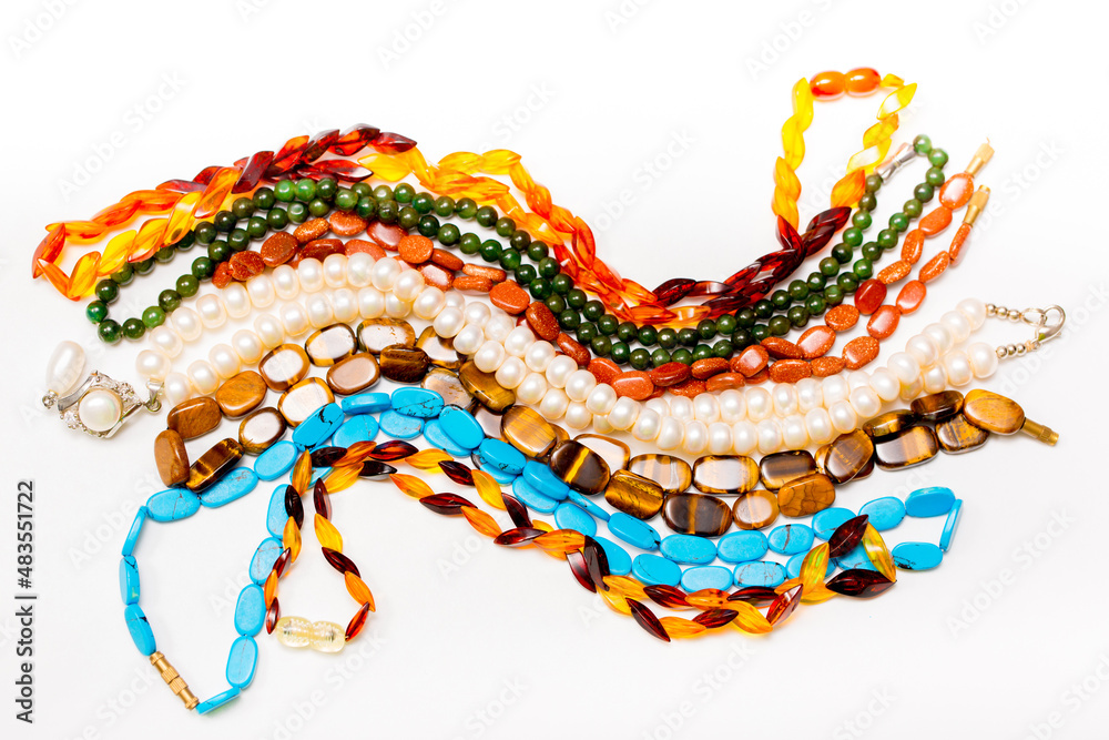 Naklejka premium Beads and necklaces made of colored semi precious stones. Background from a variety of beautiful jewelry, multi-colored turquoise stones, amber, cat's eye, pearls.