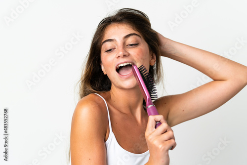 Young caucasian woman isolated on white background with hair comb and singing