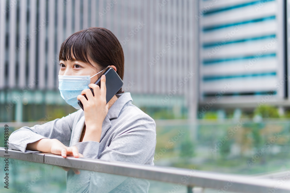 Fototapeta premium マスクをして電話をする若いビジネスウーマン