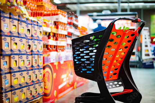 A shopping cart with grocery products in a supermarket photo