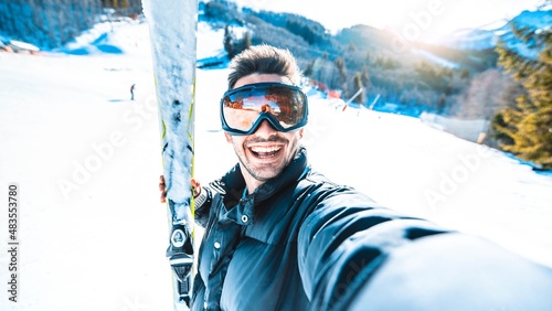 Happy skier taking selfie pic with smart cell phone device outside - Young man having fun on weekend activity in ski resort vacation - Winter sport concept 