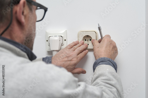 Senior electrician installing an electrical plug in a new house.