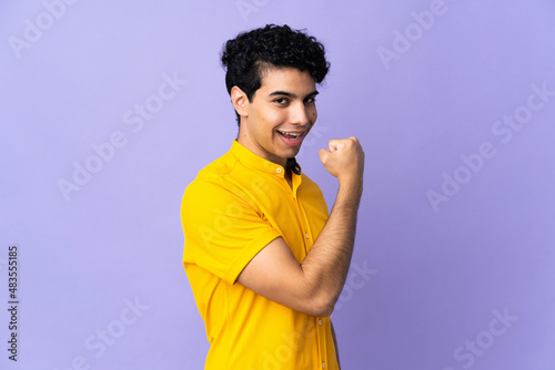 Young Venezuelan man isolated on purple background doing strong gesture