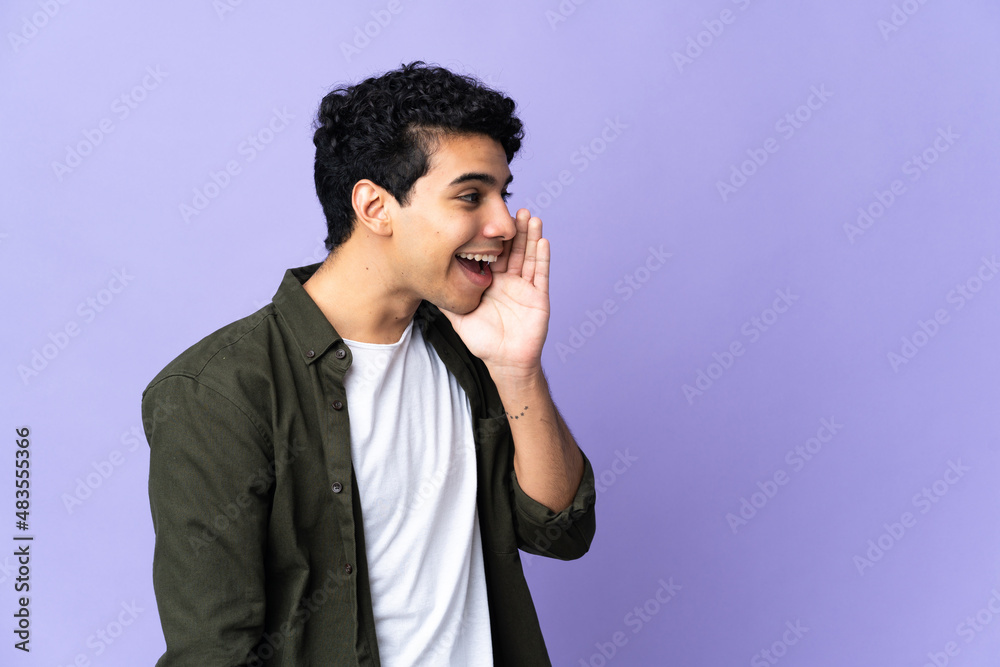 Young Venezuelan man isolated on purple background shouting with mouth wide open to the side Young Venezuelan man isolated on purple background shouting with mouth wide open to the side