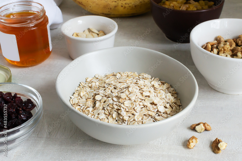 Natural and healthy ingredients for making energy bars at home. Oat flakes lie in a gray bowl with dried fruits and nuts around. Healthy food concept. Natural and healthy ingredients for making energy bars at home. Oat flakes lie in a gray bowl with dried fruits and nuts around. Healthy food concept.