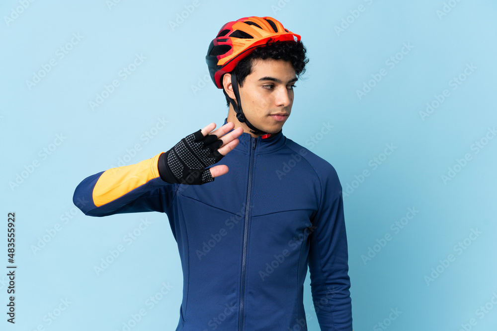 Venezuelan cyclist man isolated on blue background making stop gesture and disappointed - obrazy, fototapety, plakaty 