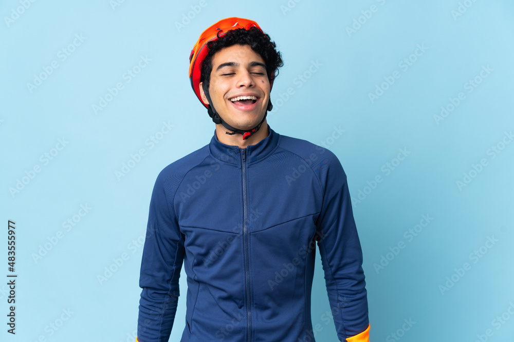 Venezuelan cyclist man isolated on blue background laughing Venezuelan cyclist man isolated on blue background laughing