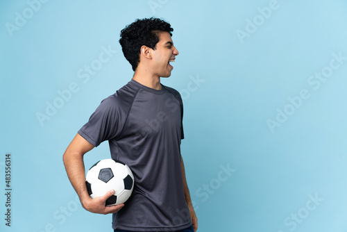 Venezuelan football player man over isolated background laughing in lateral position photo