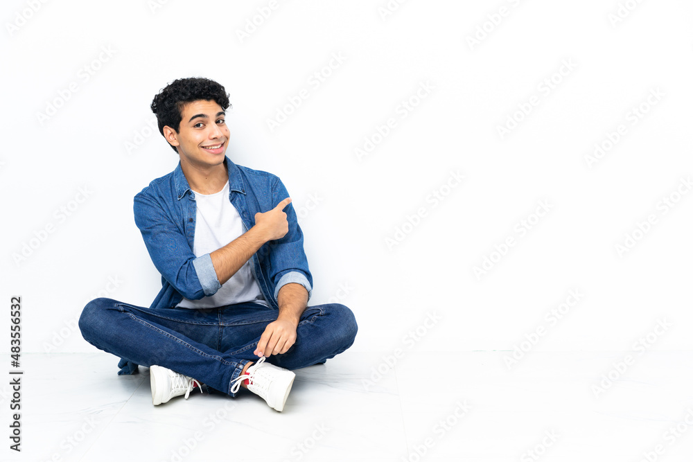 Venezuelan man sitting on the floor pointing back Venezuelan man sitting on the floor pointing back