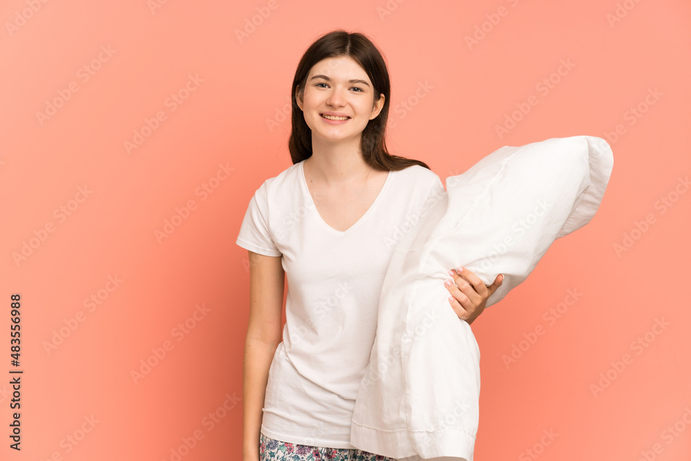 Young Ukrainian girl isolated on pink background in pajamas and smiling a lot