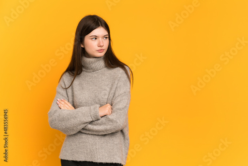 Young Ukrainian girl isolated on yellow background keeping the arms crossed © luismolinero