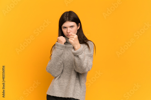 Young Ukrainian girl isolated on yellow background with fighting gesture © luismolinero