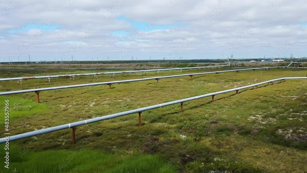 Aerial view of oil pipelines stretching across arctic tundra. Industrial infrastructure contrasts with the wild natural landscape under a cloudy sky. Aerial view of oil pipelines stretching across arctic tundra. Industrial infrastructure contrasts with the wild natural landscape under a cloudy sky.