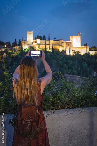 Young girl taking photos of the fortification at night