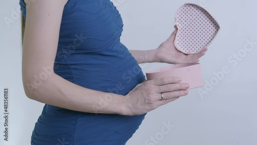 a pregnant woman in a blue dress opens a heart-shaped gift box. a gift for Valentine's Day or March 8th. video in slow motion.