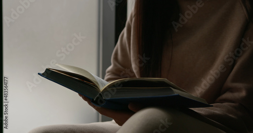 Unrecognizable woman holding book in hands, reading, turning pages. Education concept.