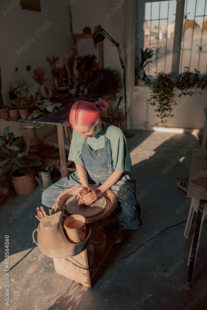 Woman crafter making clay dishes in pottery room